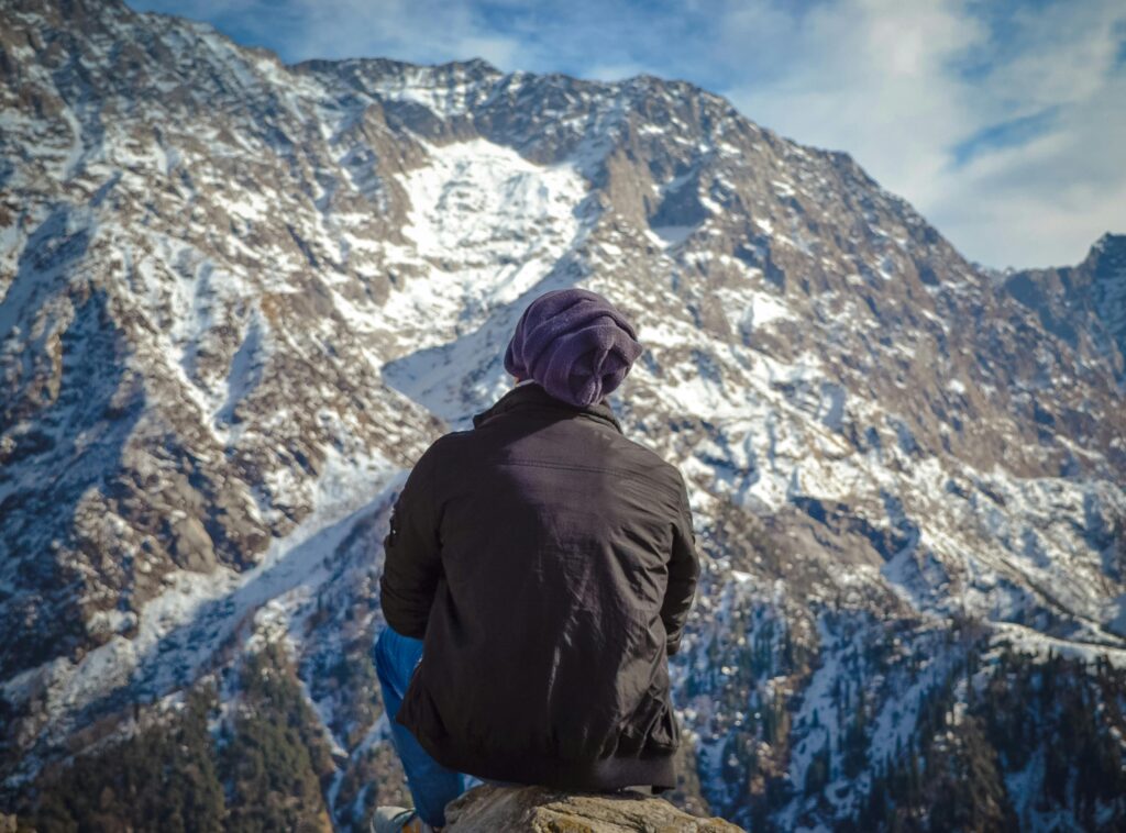 A lone trekker gazes across the snowy mountains of Dharamshala, India.
